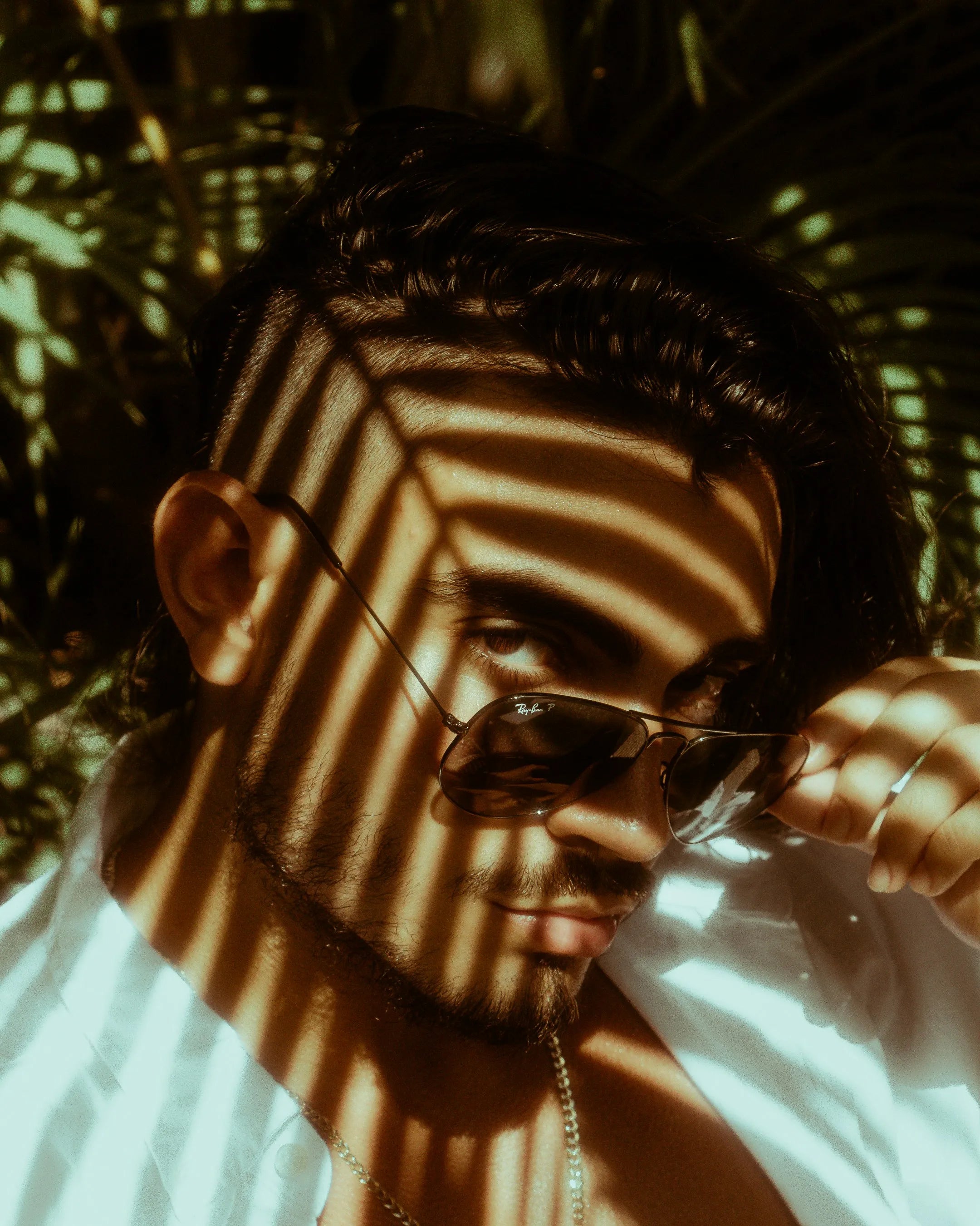 Man met zonnebril In een luxe overhemd met korte mauw waar de zon opschijnt
