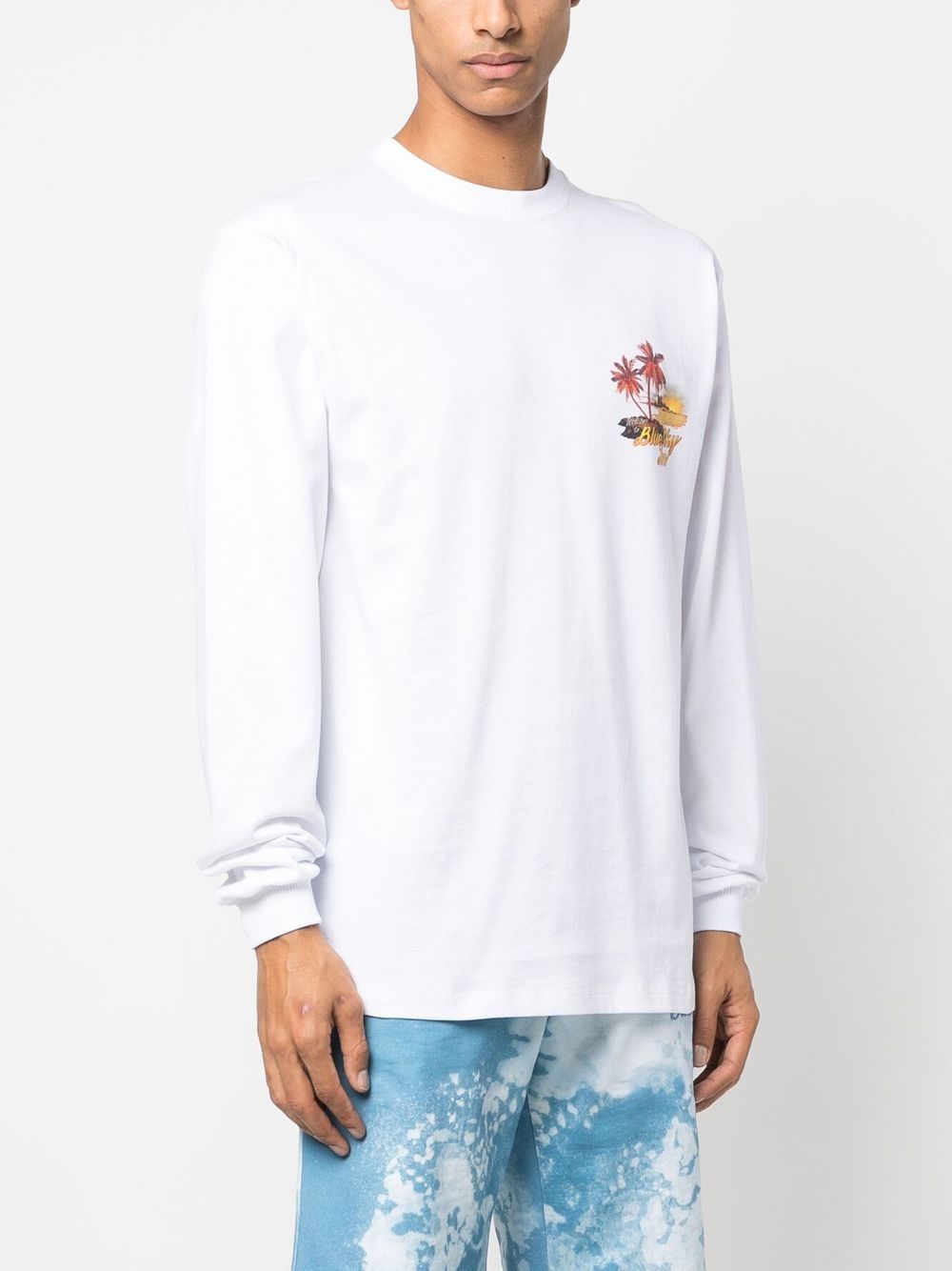 Model draagt het witte longsleeve shirt bij een lichtblauwe short