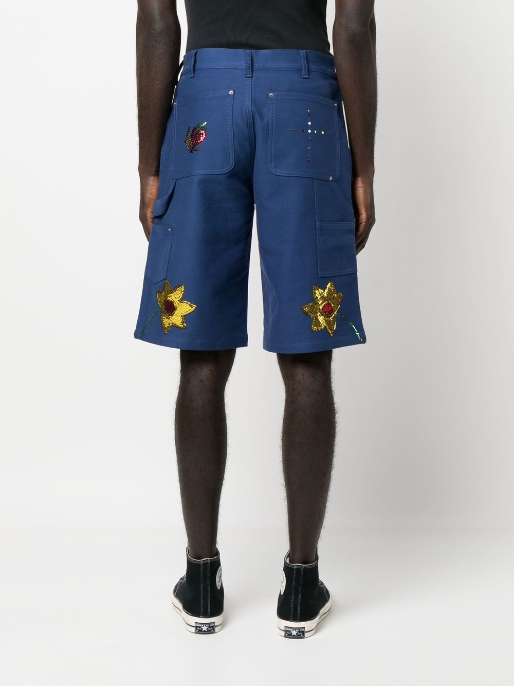 Achteraanzicht van de short met goudgele pailletbloemen en patchachterzakken met klinknagels