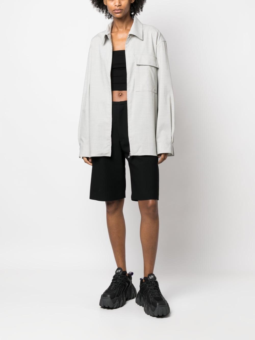 Model draagt het overshirt open over een zwarte top en zwarte short