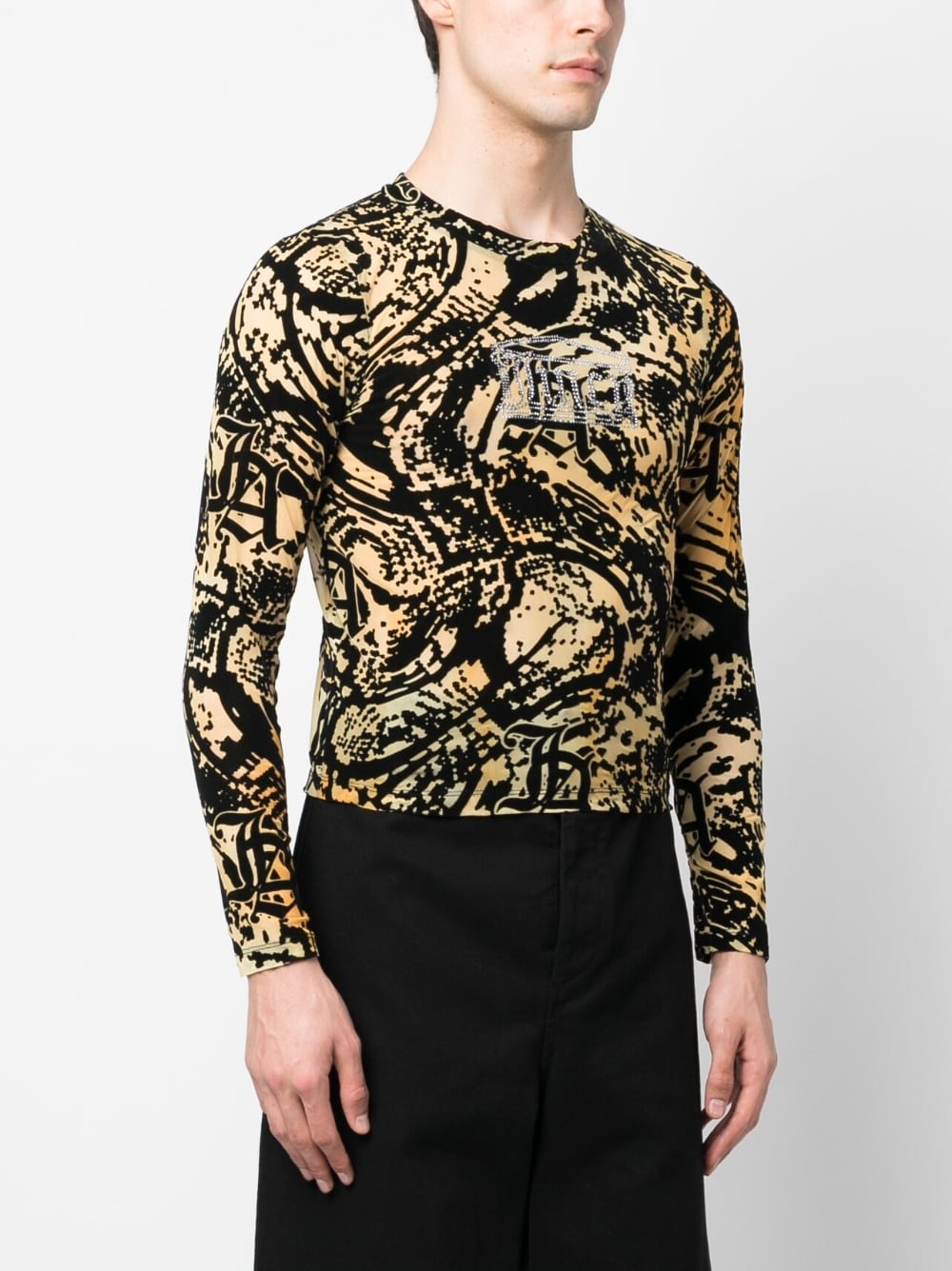 Model draagt de nauwsluitende mesh longsleeve bij een zwarte broek
