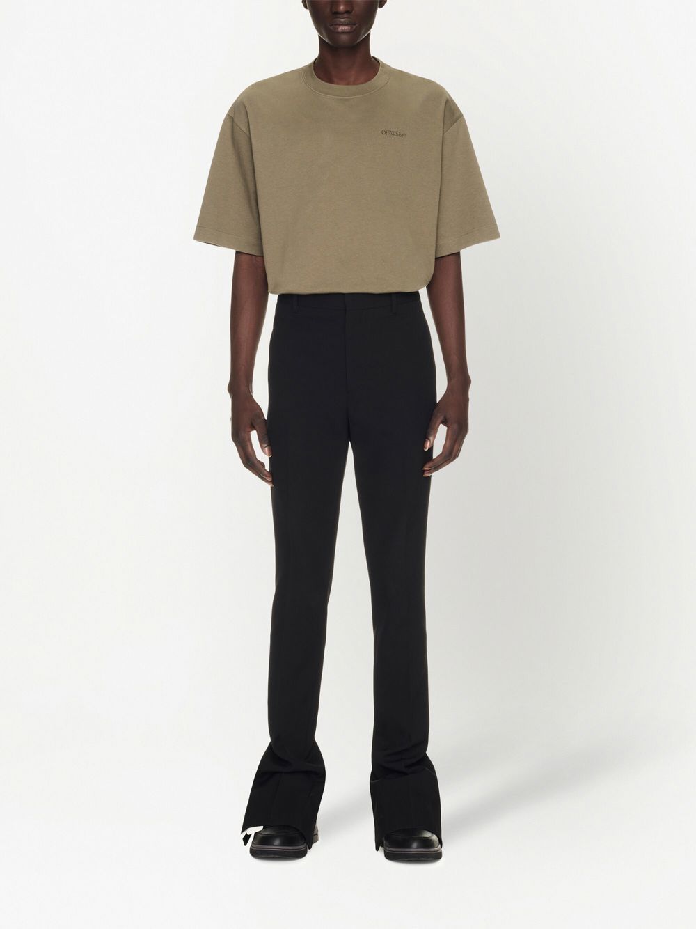 Pantalon gedragen bij een oversized T-shirt, met gesplitte zoom over de schoen