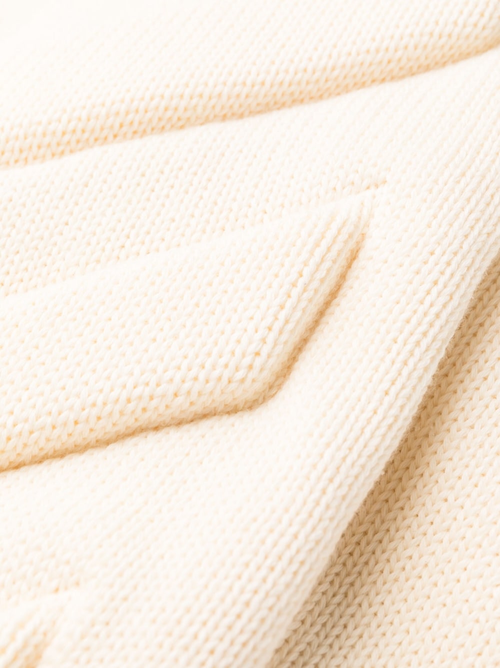 Close-up van het grove honingraatbreisel van de crèmekleurige trackpants