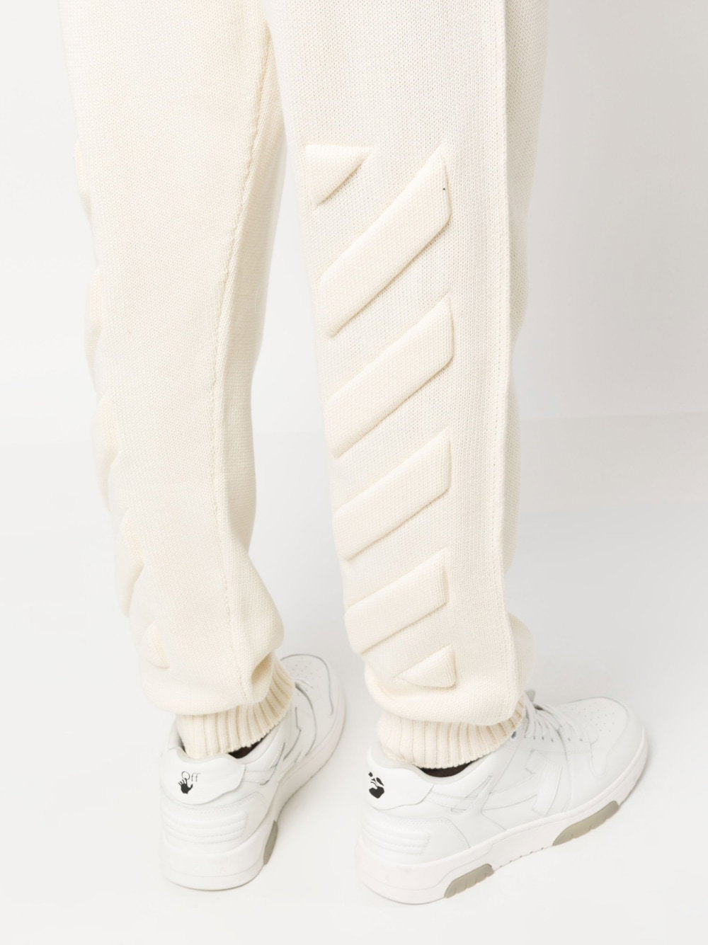 Detail van de Diag-ribbels in reliëf en de geribde enkelboorden boven witte sneakers