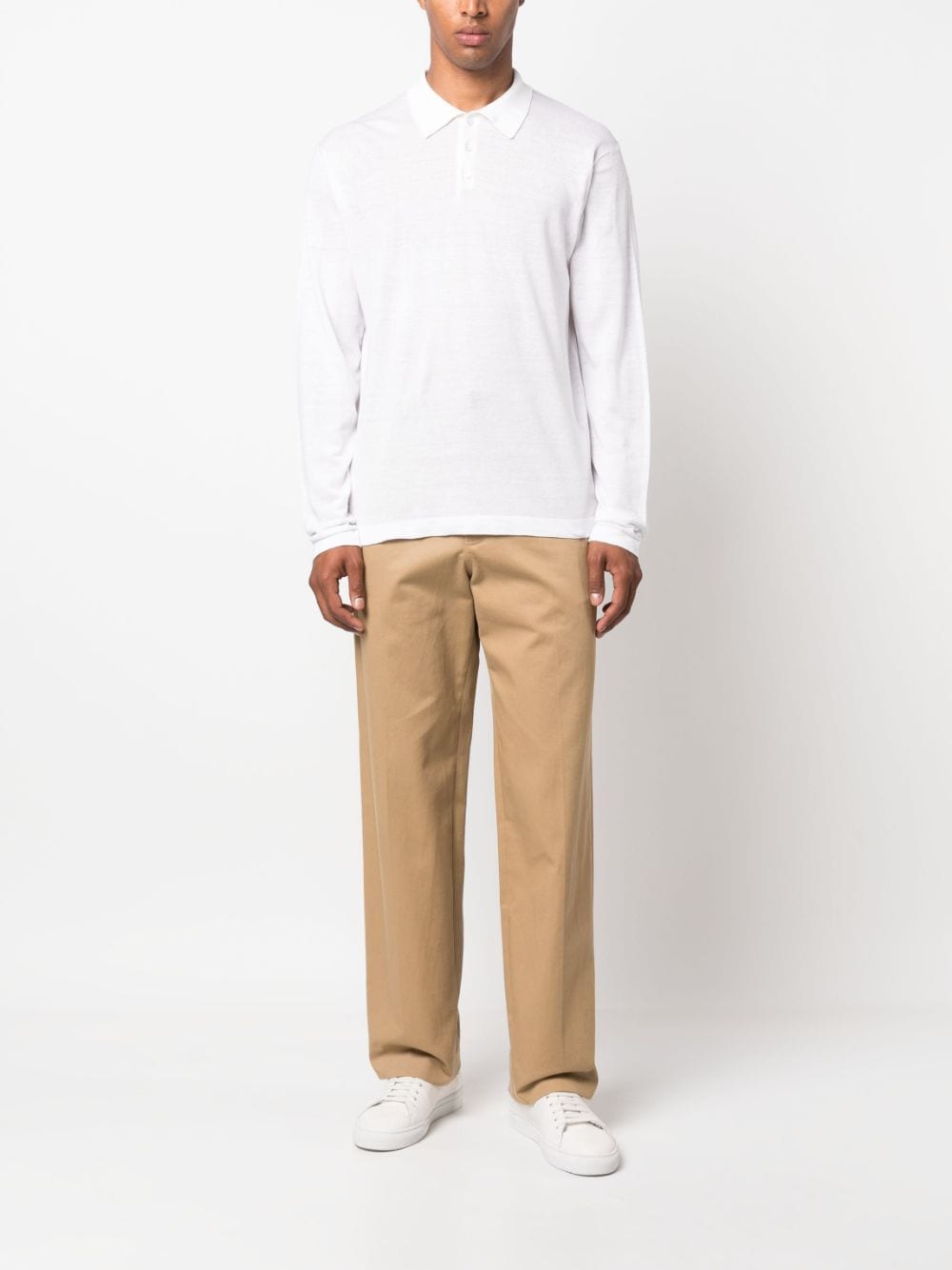 Model draagt de witte polo bij een camelkleurige chino en witte sneakers