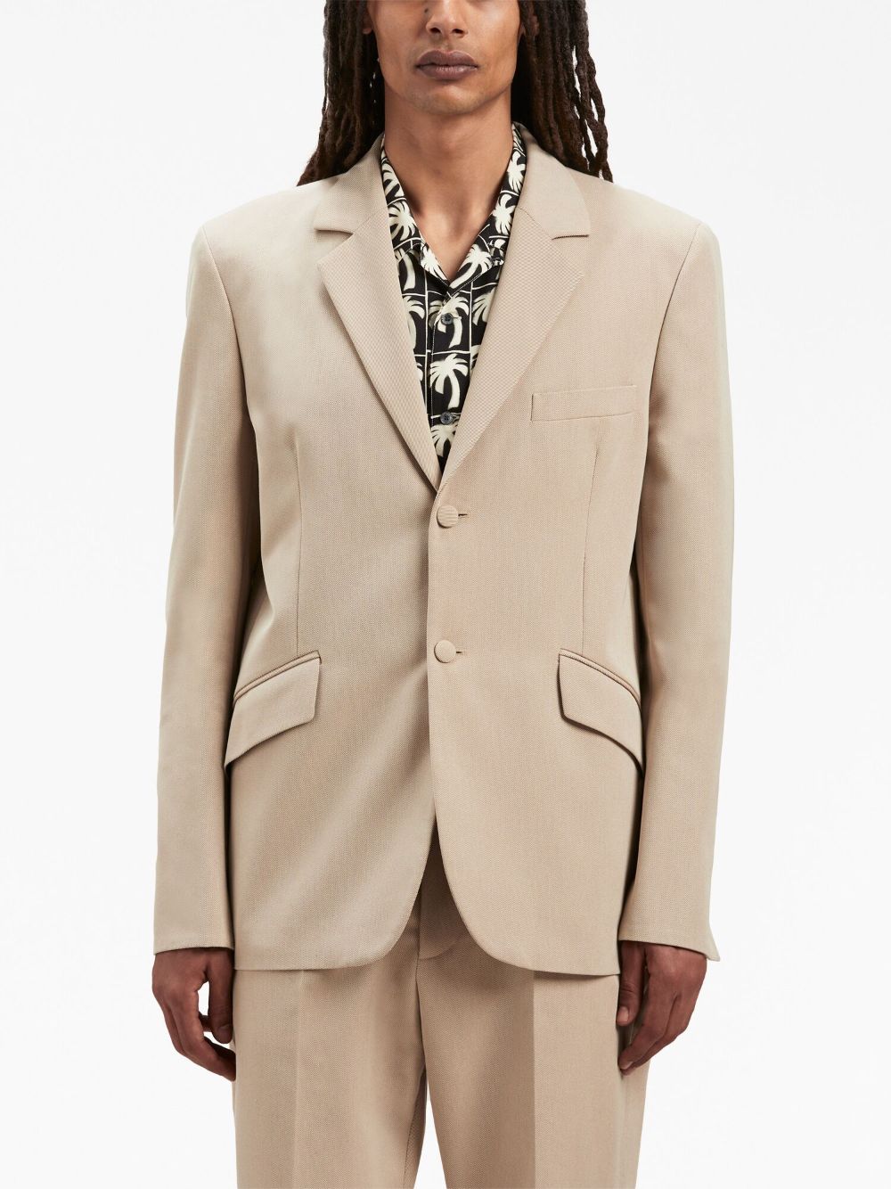 Model draagt de zandbeige Palm Angels blazer over een T-shirt