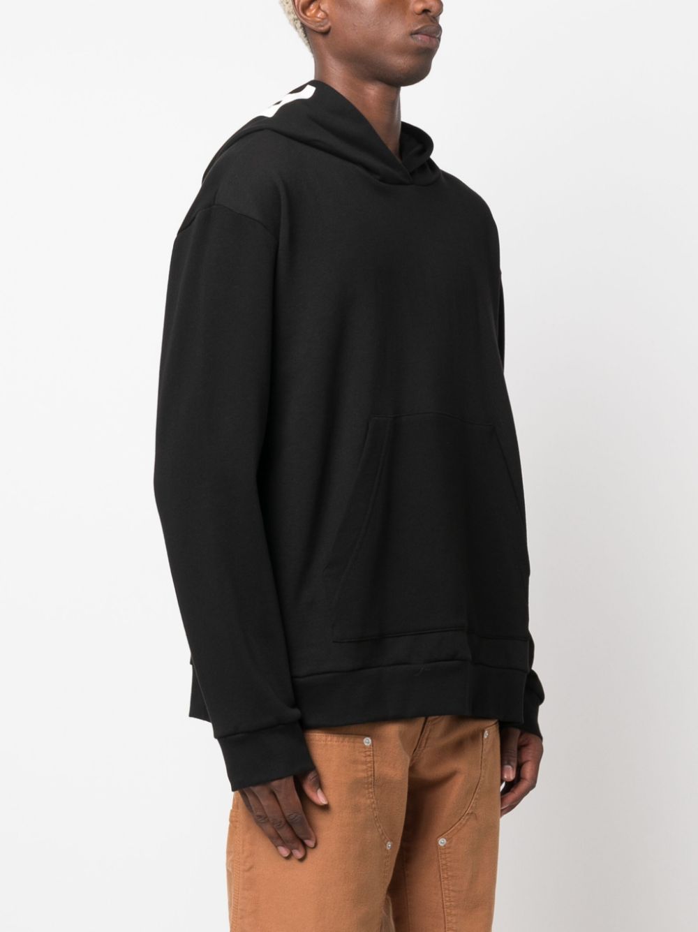 Zwarte hoodie gedragen, driekwart aanzicht met verlaagde schouder en brede mouw