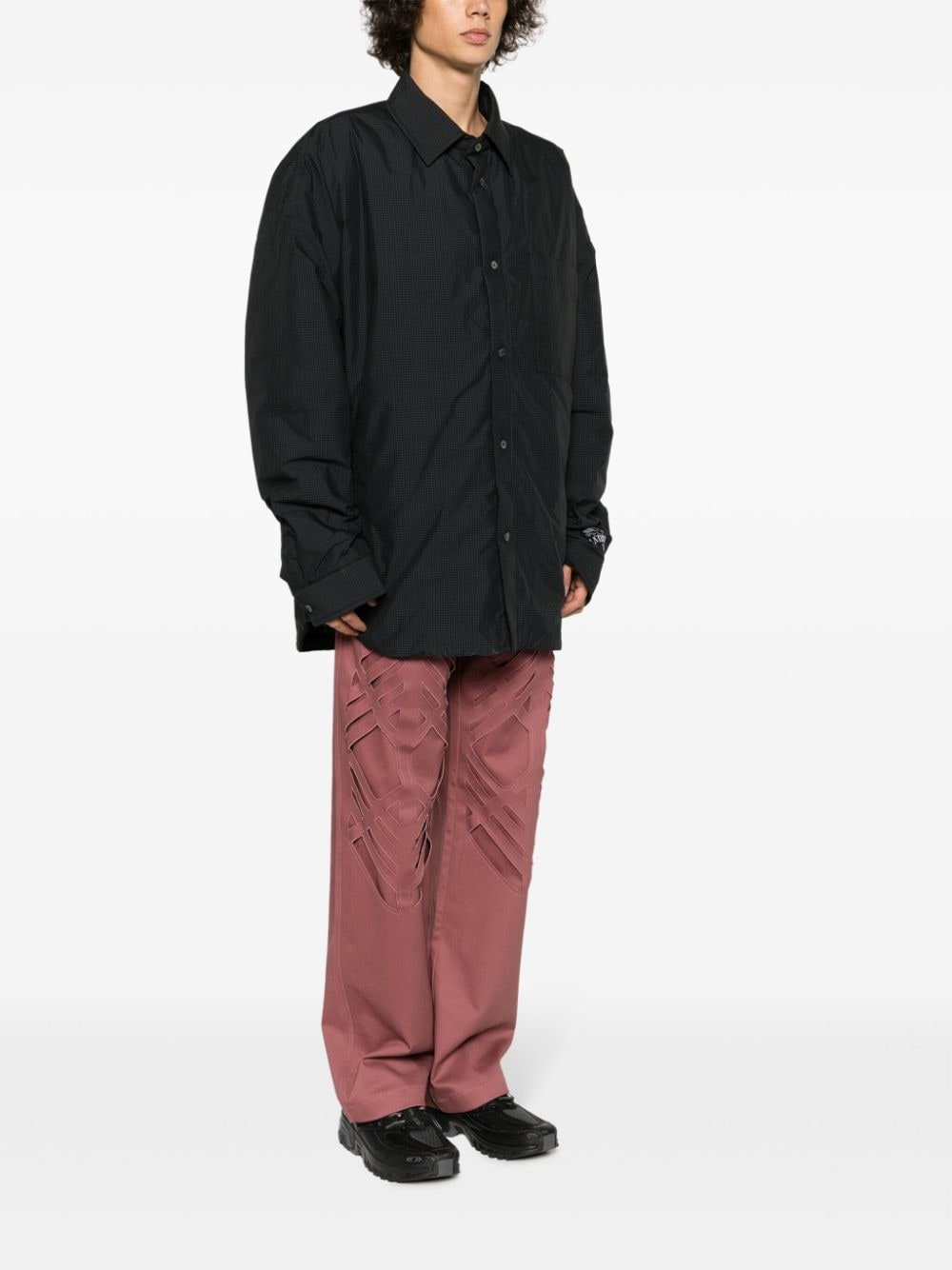 Model draagt het overshirt open boven een roze pantalon, zijaanzicht