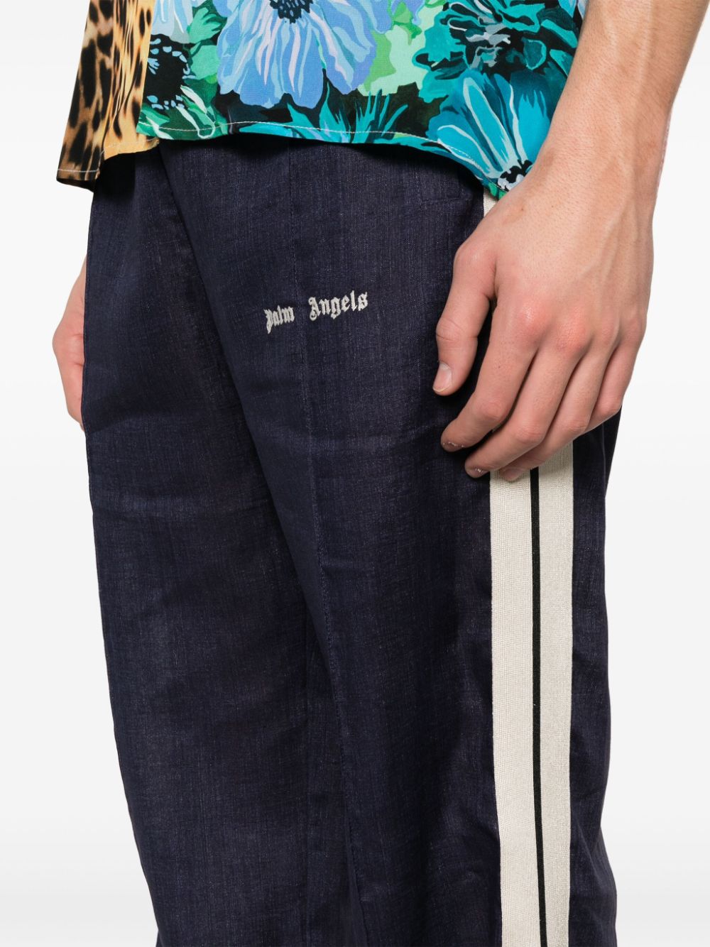Detail van het witte geborduurde Palm Angels-logo op de dij
