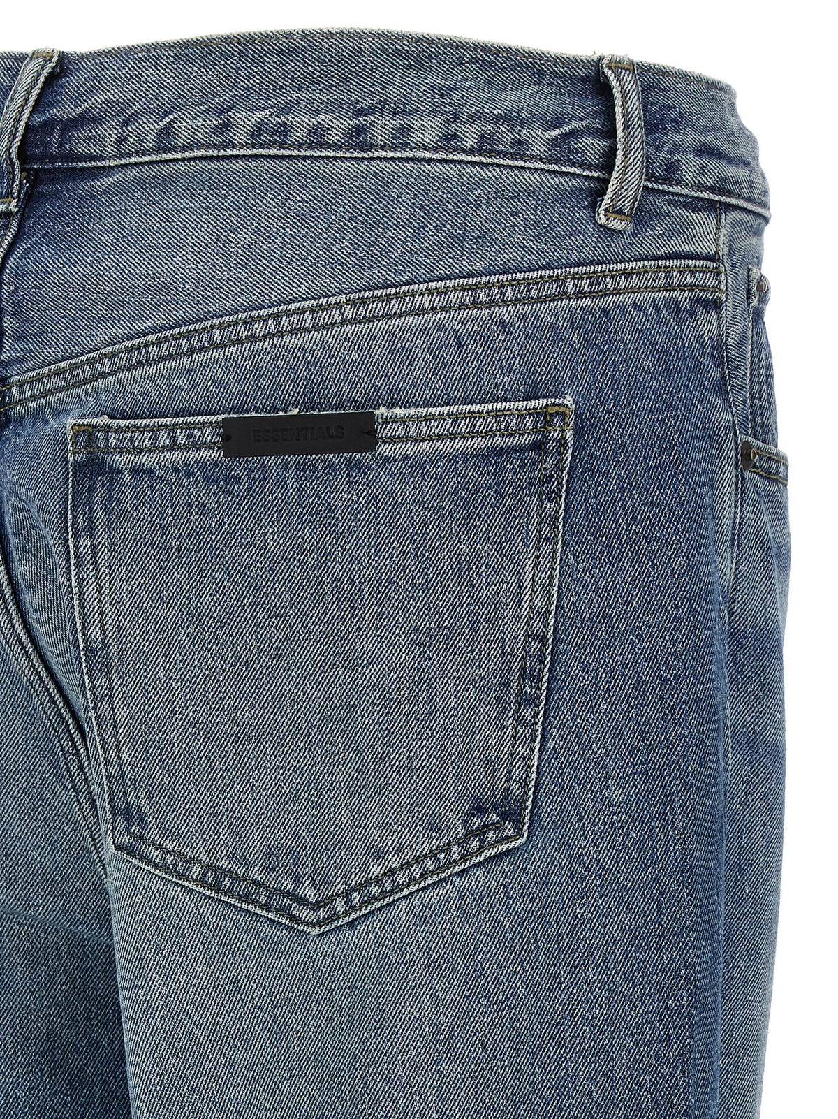 Detail van de achterzak met het kleine zwarte rubberen Essentials-label