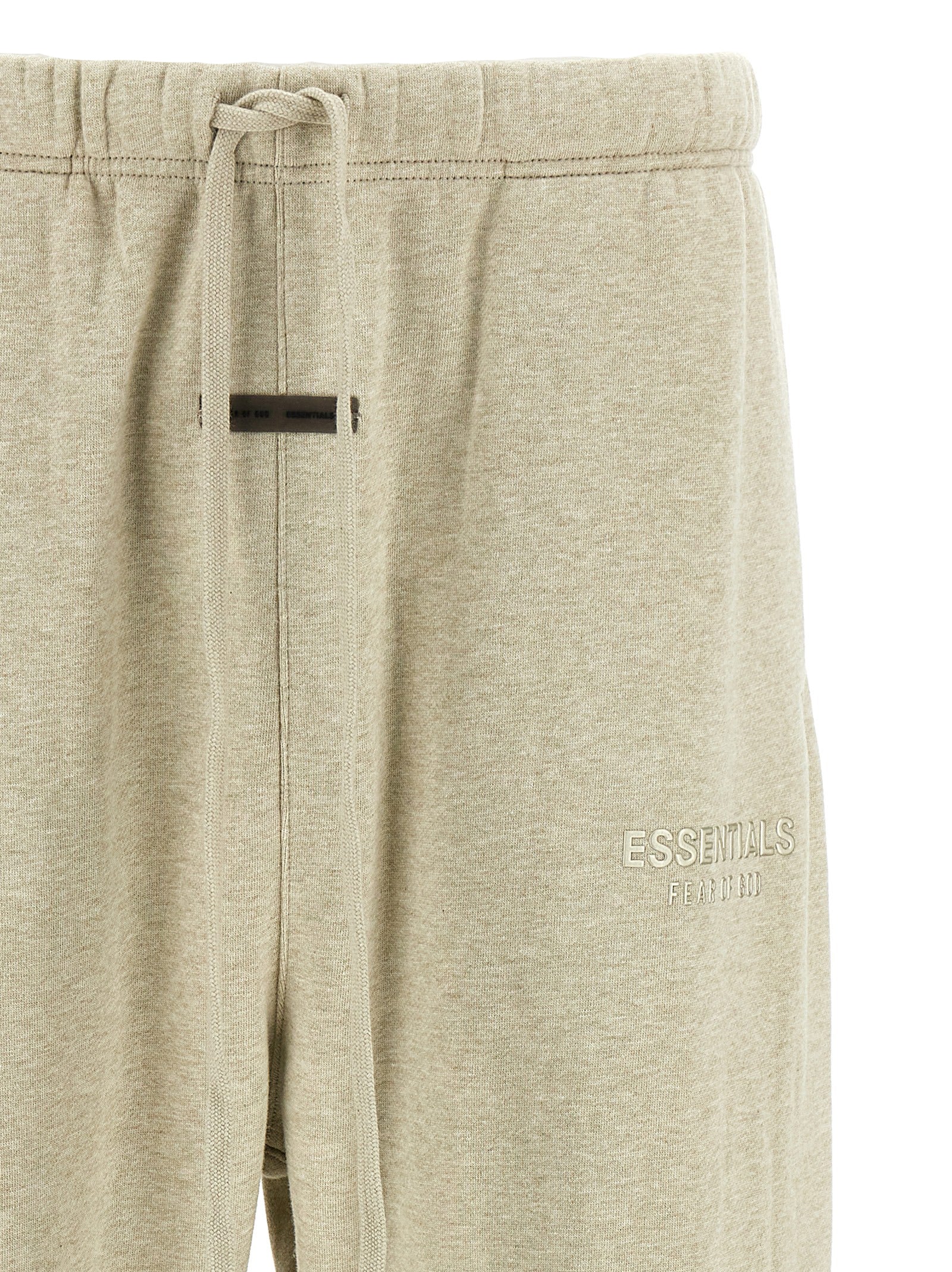 Detail van de elastische taille met trekkoord en het tonaal geborduurde Essentials-logo