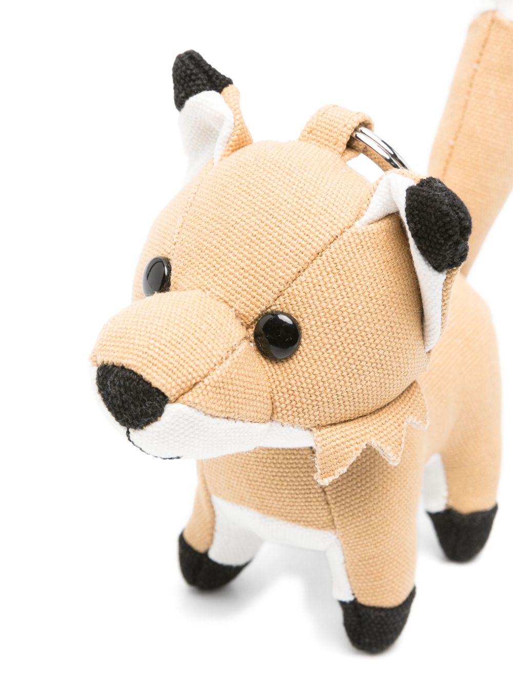 Zijaanzicht van de Maison Kitsuné vos-bagcharm met zwarte oorpunten, witte snuit en opstaande staart