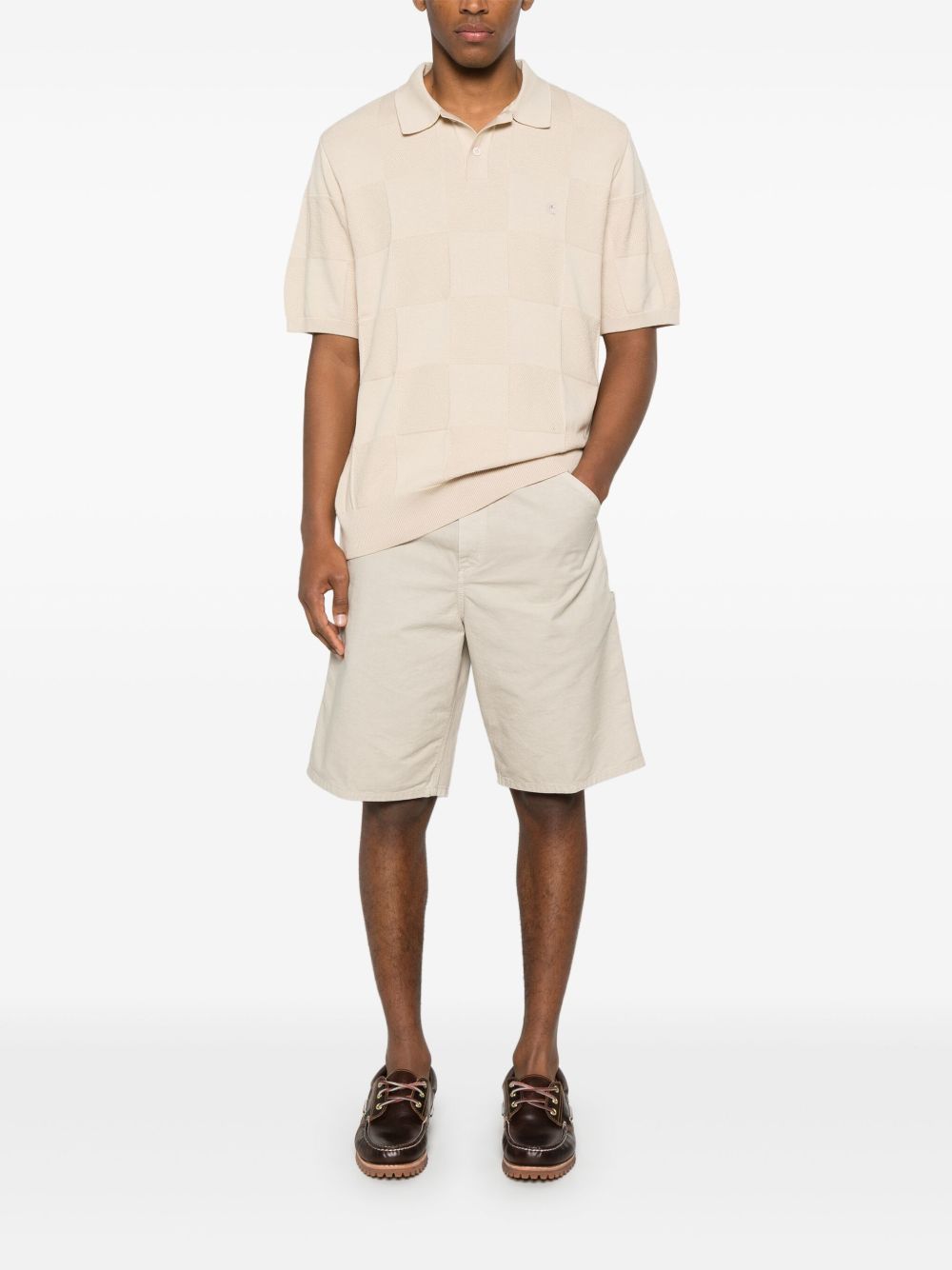 Model van voren in de gebroken witte short met beige polo en bootschoenen