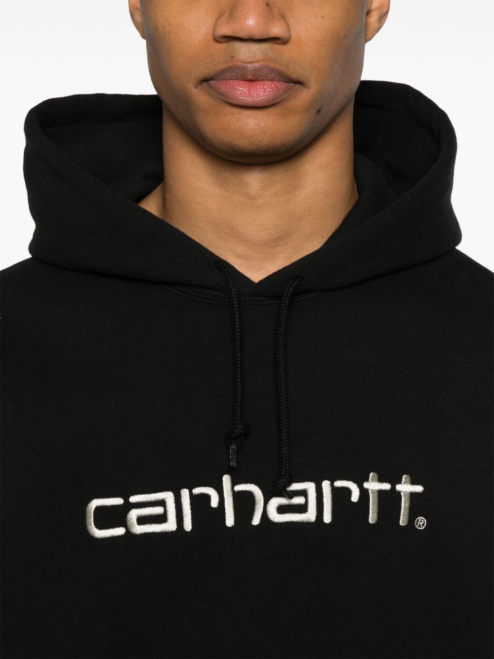 Detail van de capuchon met trekkoord en het beige geborduurde Carhartt-logo