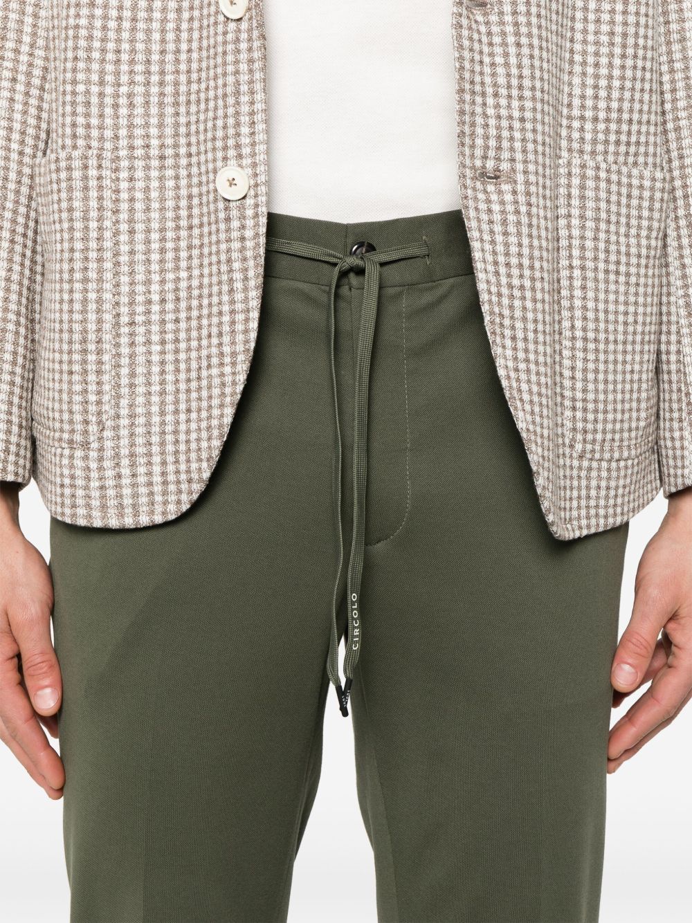 Detail van de tailleband met trekkoord van de groene Circolo 1901 broek onder een geruite blazer