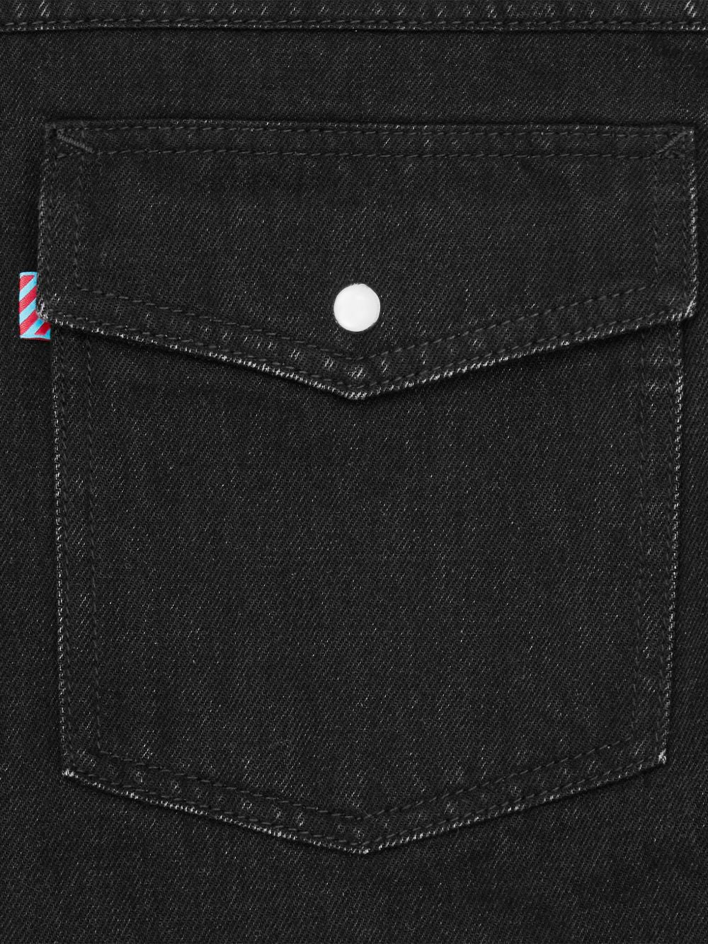 Detail van de borstzak met klep, witte drukknoop en het rood-wit-blauwe streeplabel