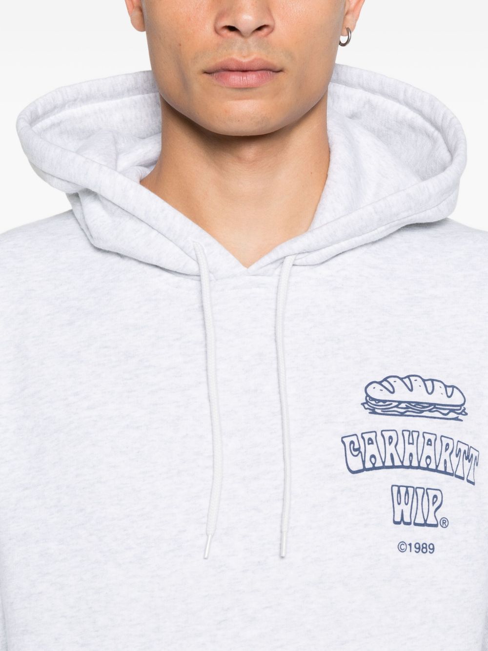 Detail van de blauwe borstprint met sandwich, Carhartt WIP in bolle letters en 1989