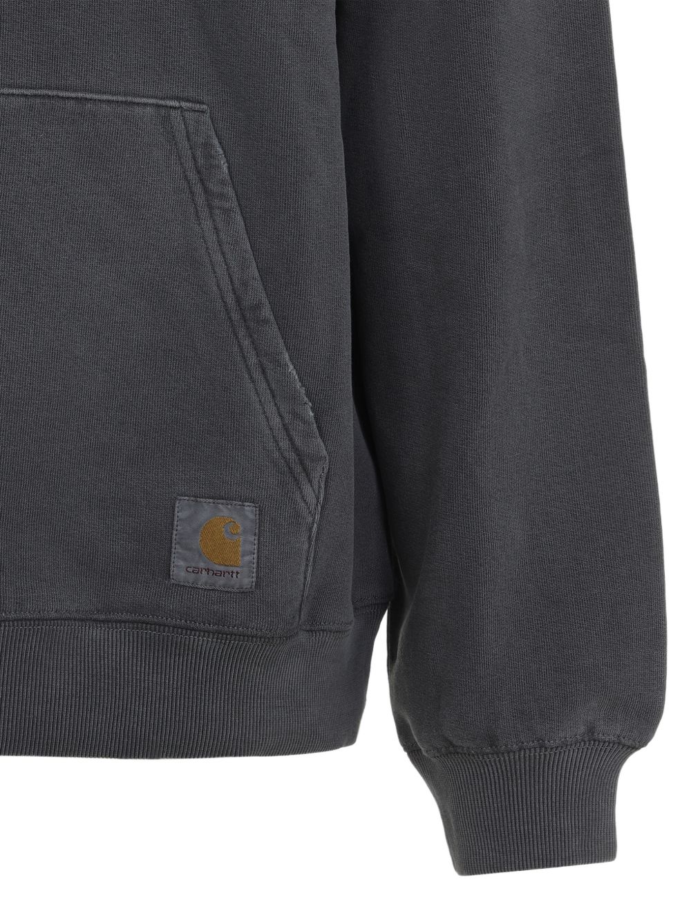 Detail van het vierkante Carhartt-label op de kangoeroezak en de geribde manchet