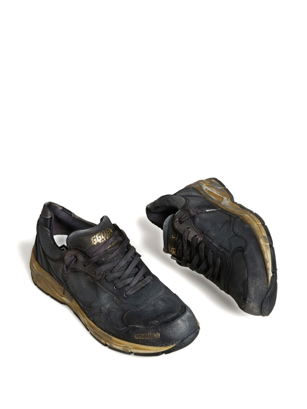 Bovenaanzicht van beide zwarte Dad-Star sneakers met gouden logo-opdruk op de tong