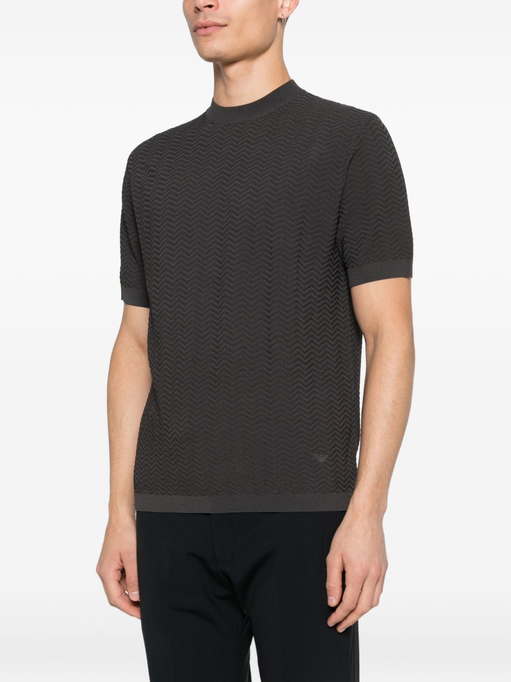 Model draagt het donkerbruine gebreide T-shirt met ronde hals