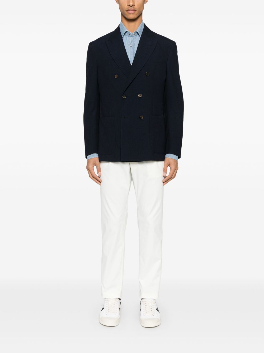 Model draagt de witte pantalon bij een donkerblauw jasje