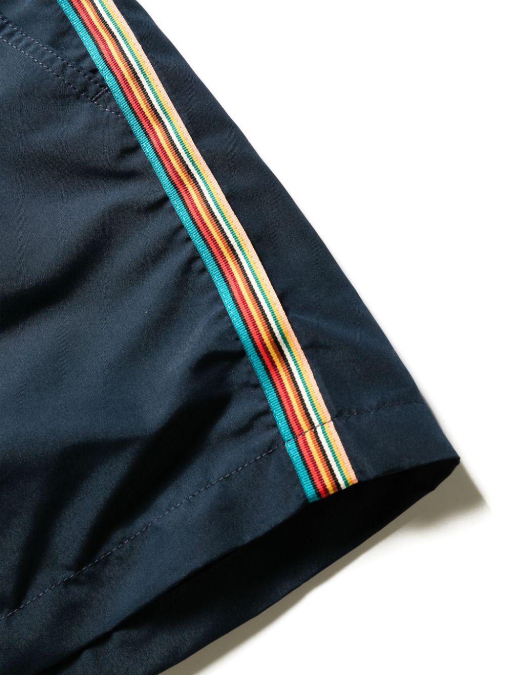 Close-up van de geweven Signature Stripe in turquoise, crème, oranje en rood op de zijnaad