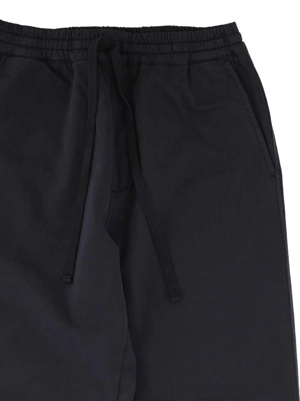 Detail van de elastische tailleband met trekkoord en de verticale steekzak in de zijnaad