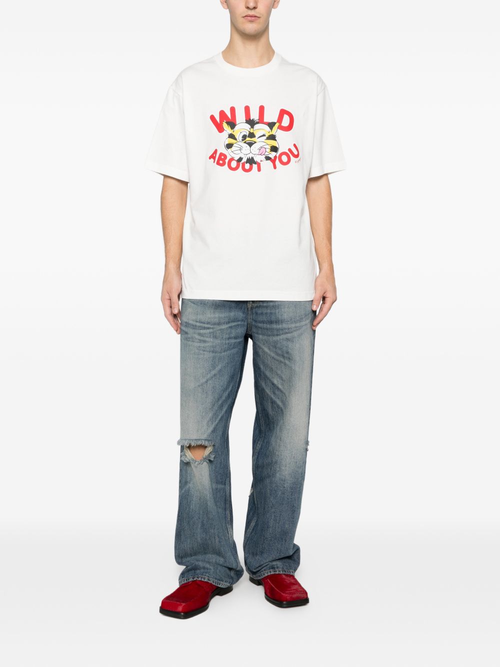 Model draagt het T-shirt bij een lichte jeans, volledig beeld