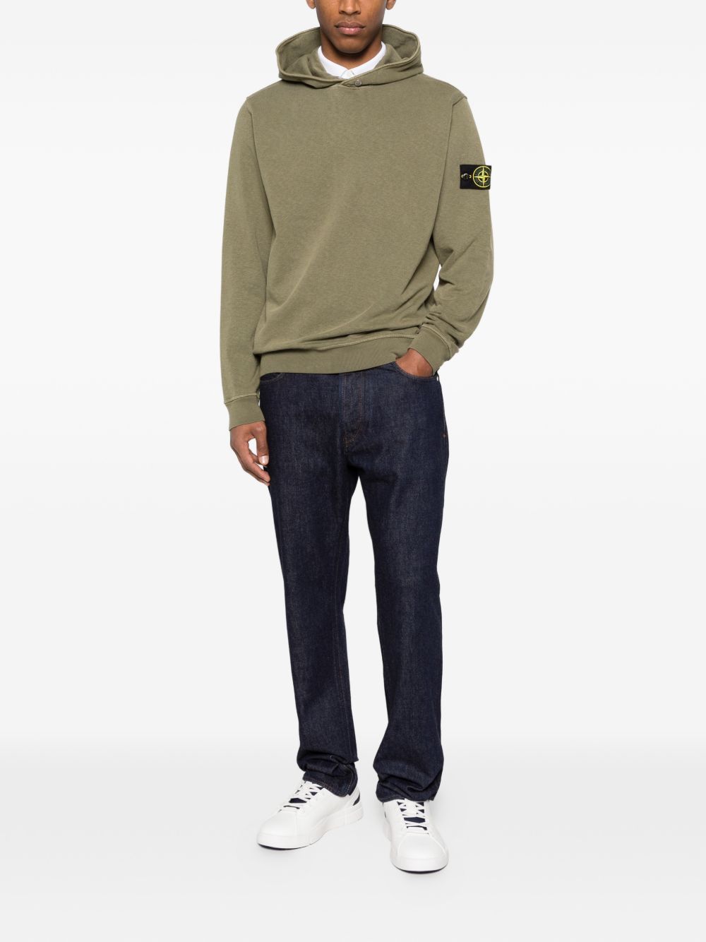 Model draagt de legergroene Stone Island hoodie bij een donkere jeans