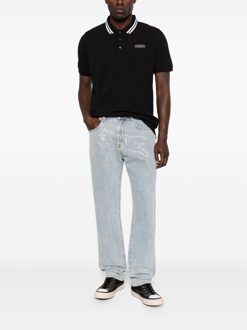 De jeans gedragen bij een zwarte polo, zijaanzicht
