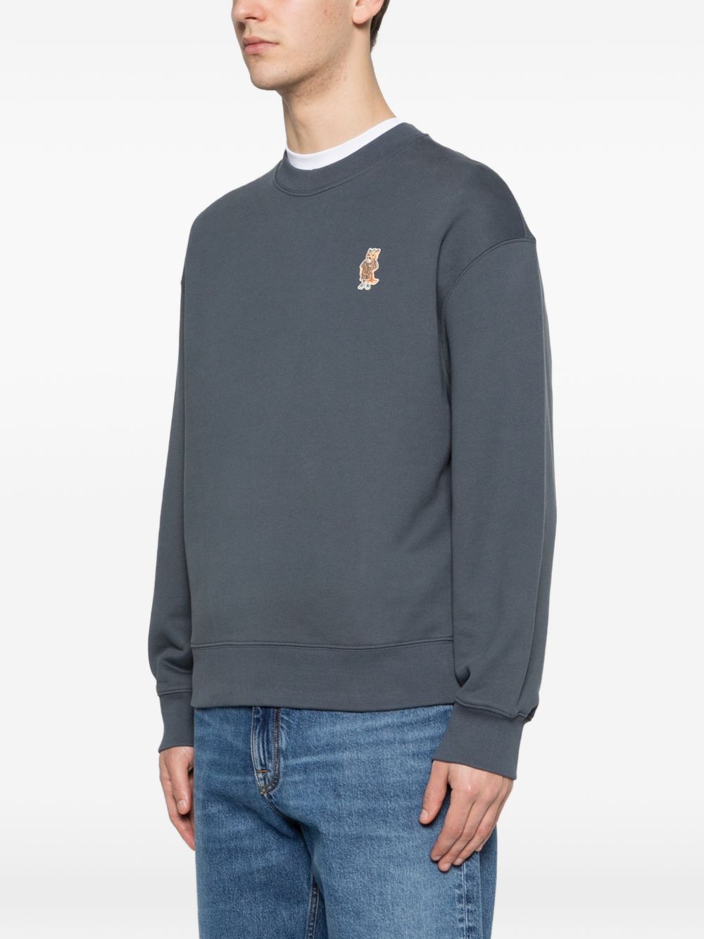 Model draagt het blauwgrijze Maison Kitsuné sweatshirt, zijaanzicht