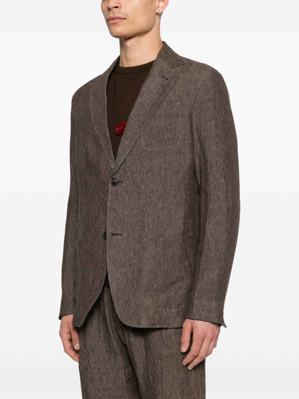 Model draagt de bruine linnen blazer over een donkere trui