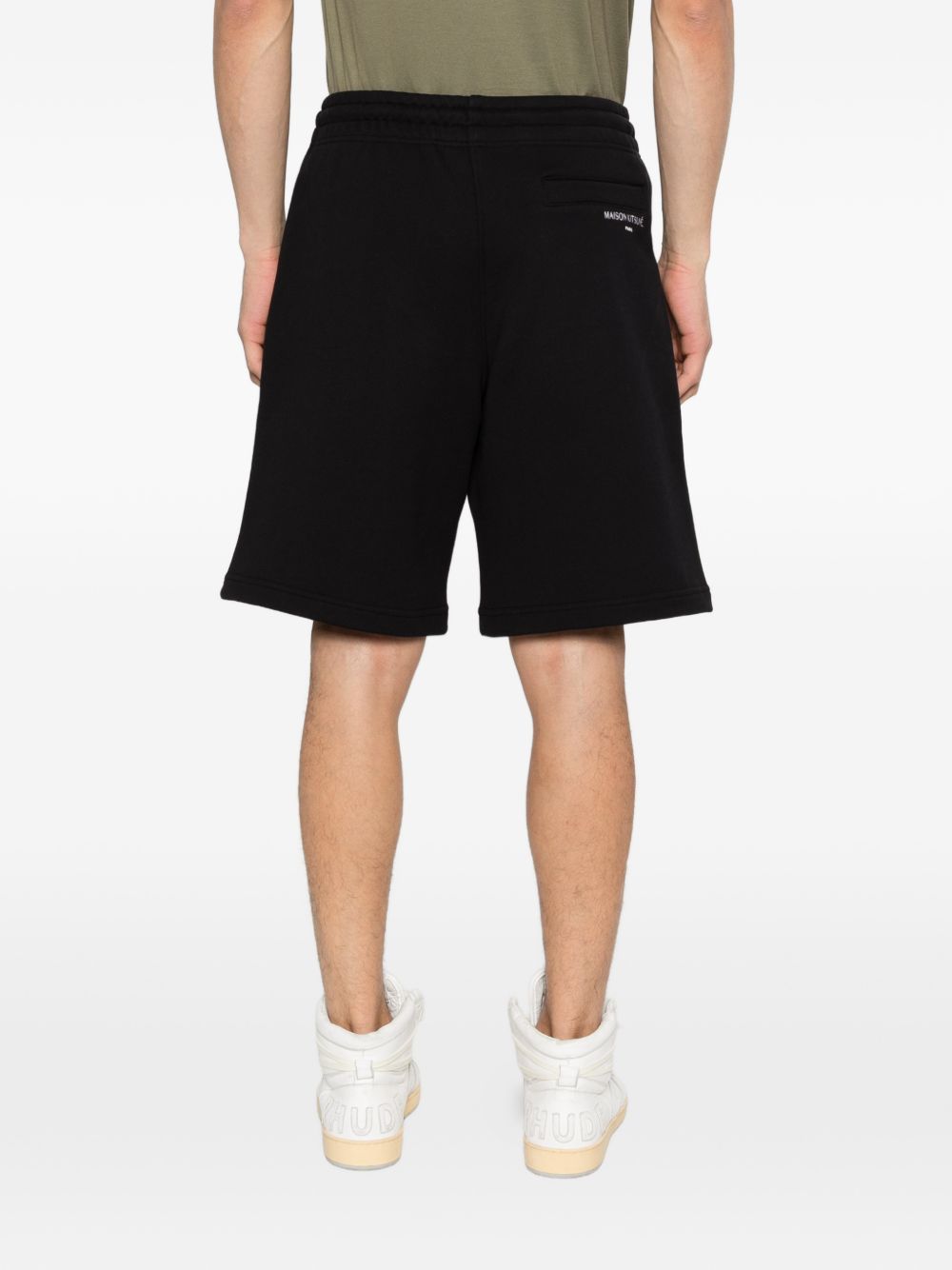 Model draagt de zwarte oversize jog short, achteraanzicht met paspelzak