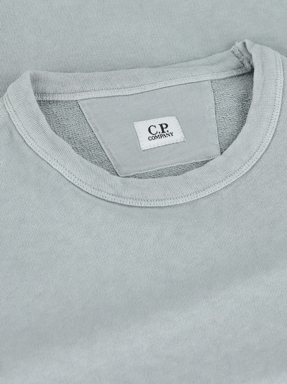 Detail van de geribde halsboord met het witte C.P. Company-label en de opgeruwde binnenkant