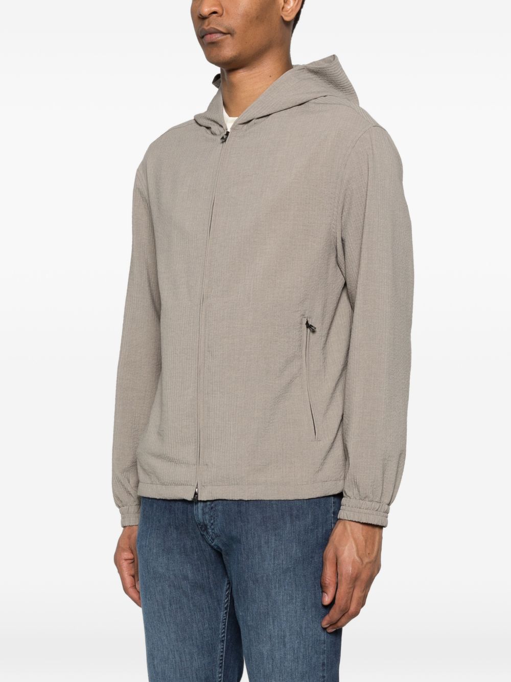 Model draagt het beige seersucker blouson van Emporio Armani over een poloshirt
