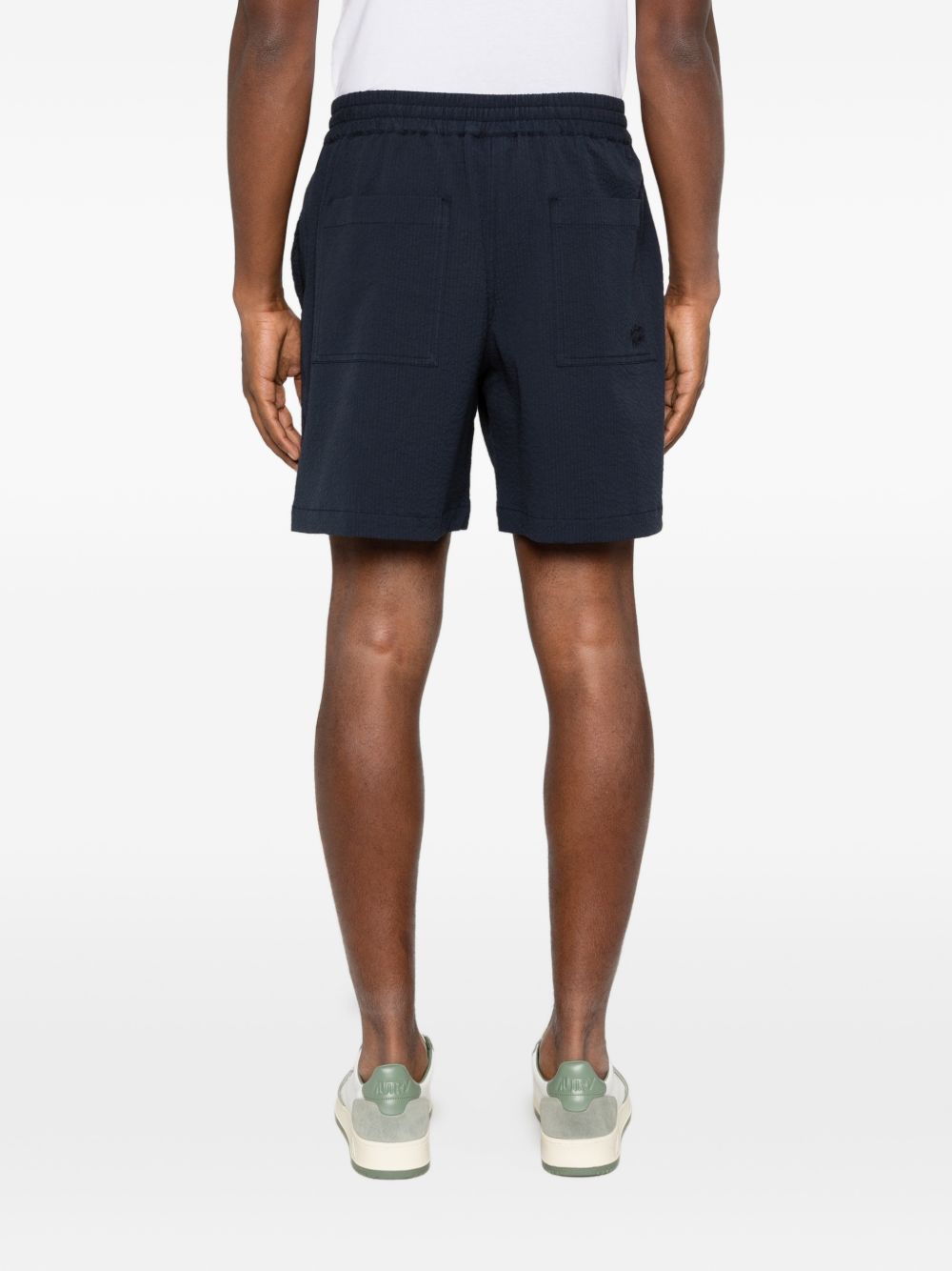 Model draagt de marineblauwe Maison Kitsuné seersucker short, pijp tot boven de knie