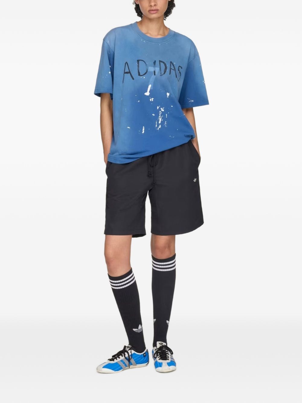 Model in volle lengte met de Adidas x Song For The Mute 007 short en hoge sokken