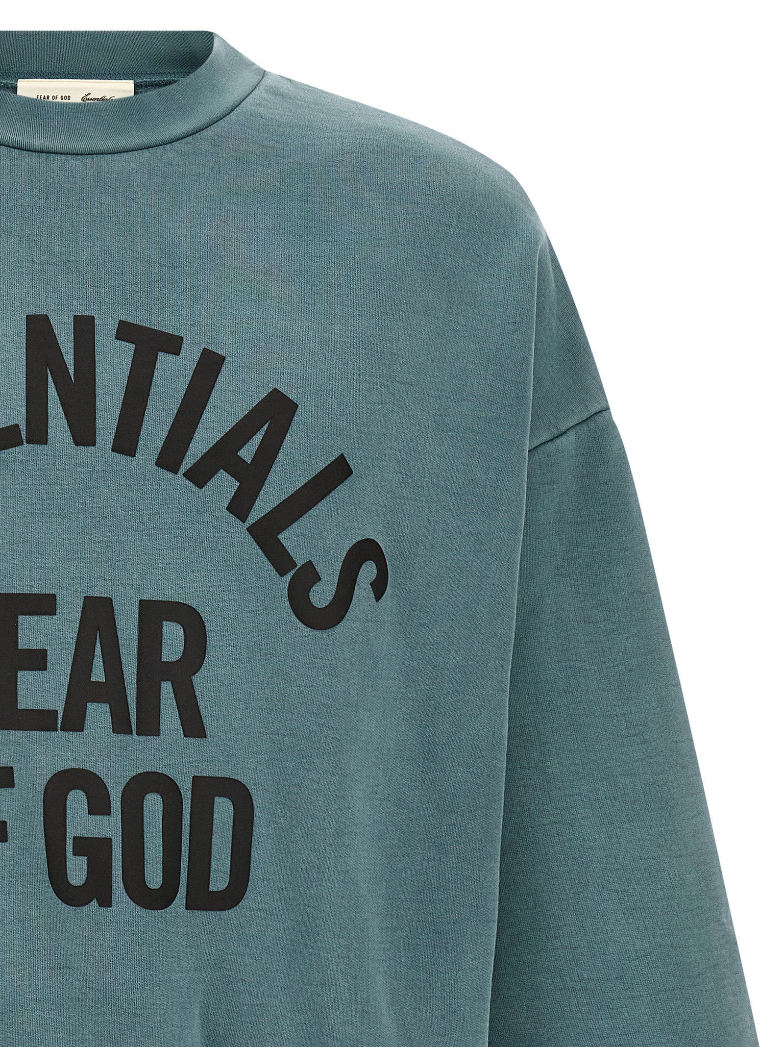 Detail van de matte zwarte ESSENTIALS FEAR OF GOD-belettering op de borst
