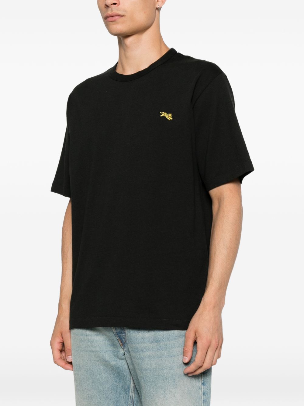 Model draagt het zwarte T-shirt met de geborduurde tijger op de linkerborst