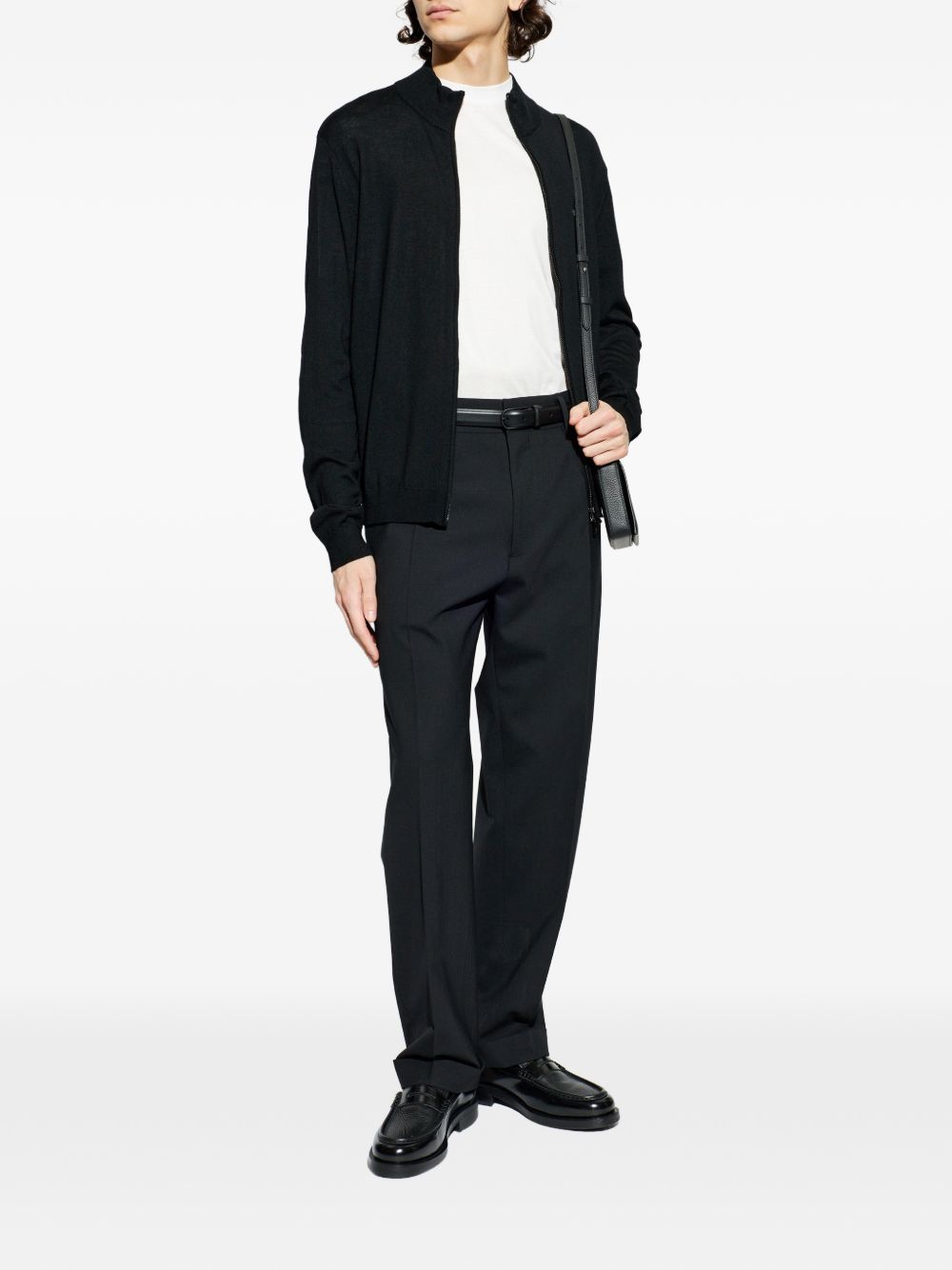 Het vest open gedragen over een wit shirt met een zwarte broek