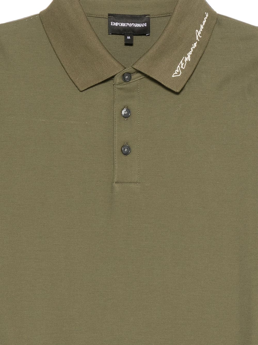 Detail van de wit geborduurde Emporio Armani-signatuur op de kraag
