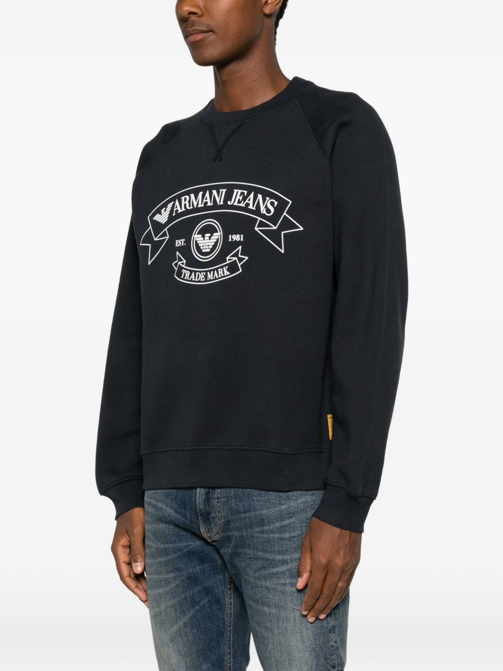 Detail van de Armani Jeans-logoprint op de navyblauwe sweater