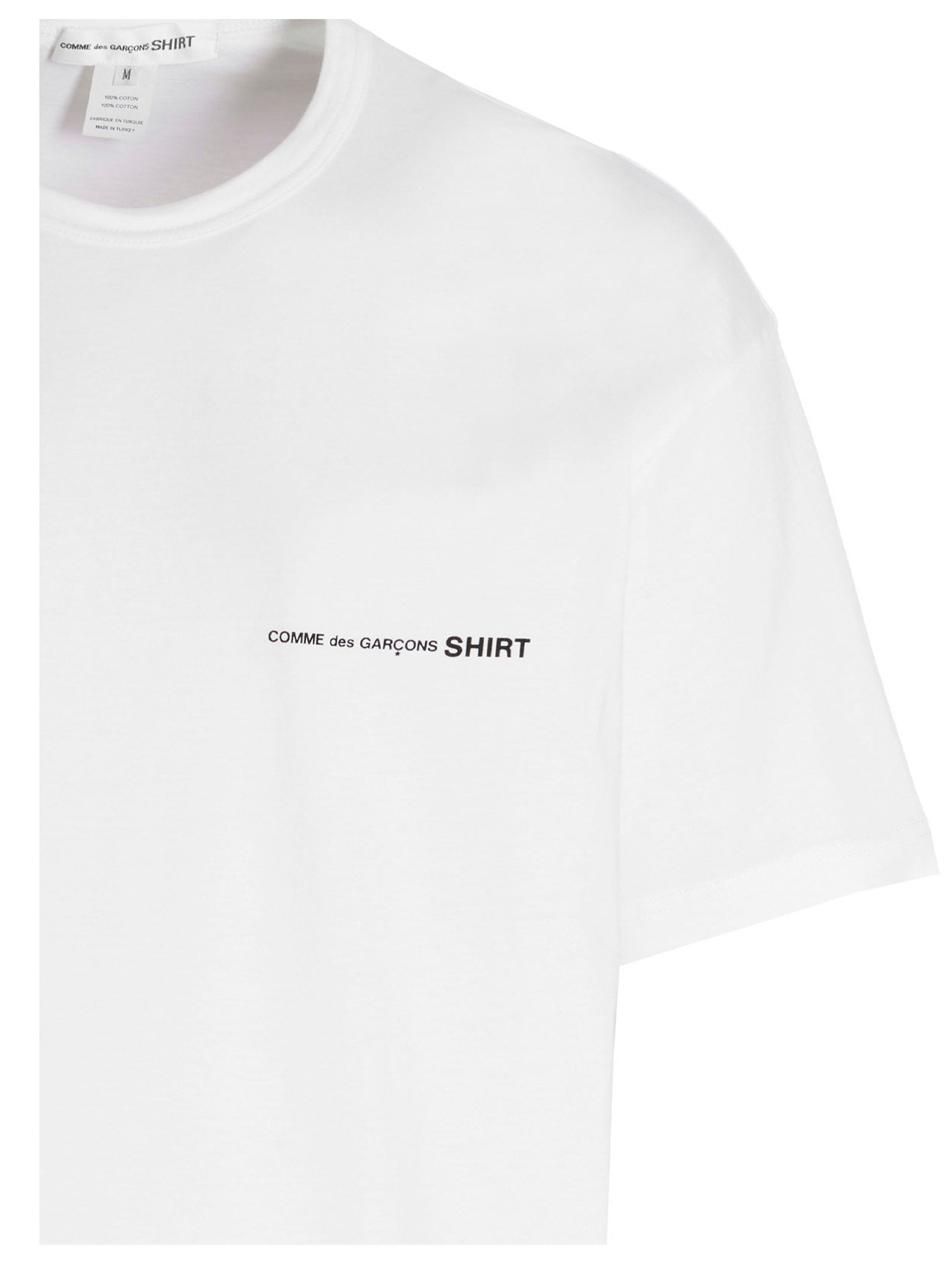 Detail van de zwarte tekst COMME des GARÇONS SHIRT op de borst