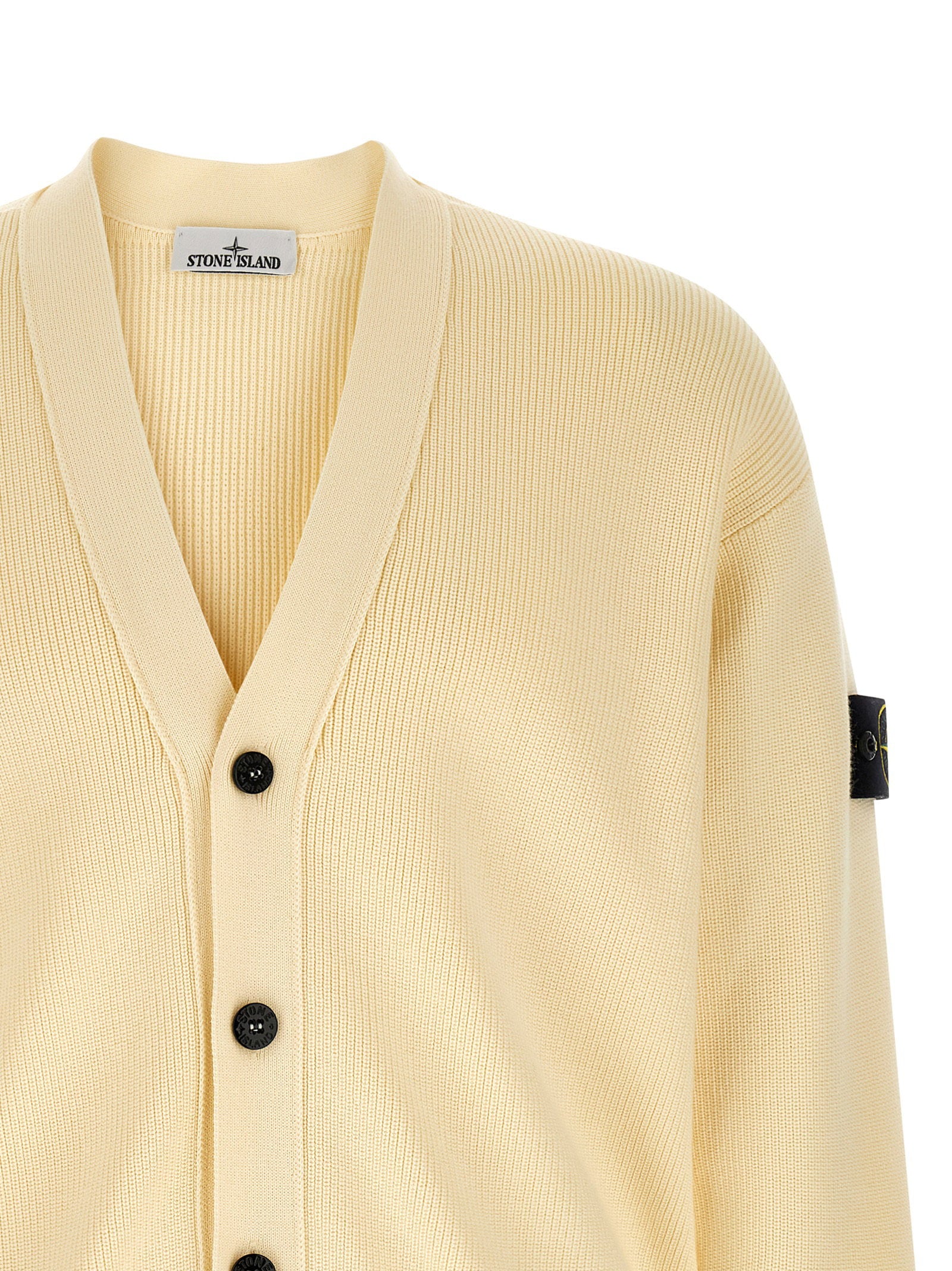 Detail van de V-hals met brede geribde bies en het geweven Stone Island-label
