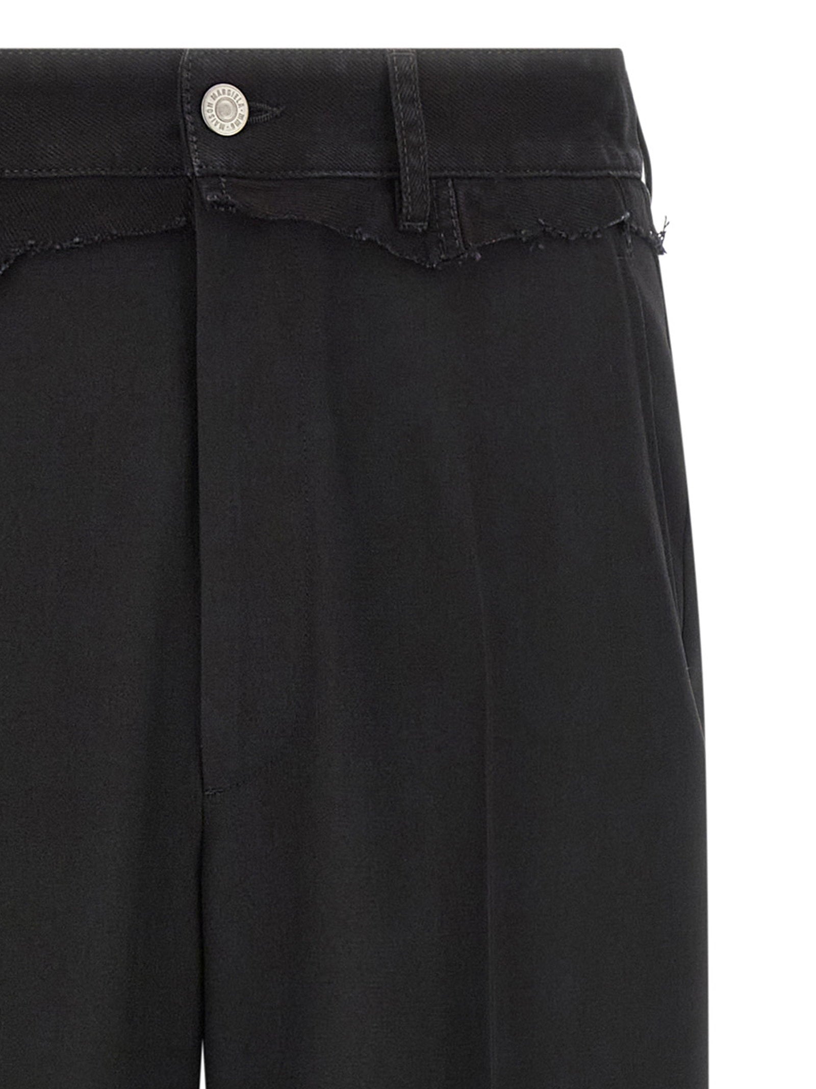 Detail van de denim tailleband met jeansknoop, riemlussen en rauwe rafelrand
